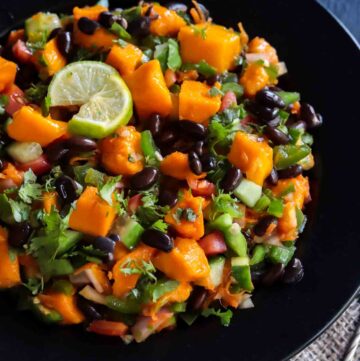 Vegan Black Bean Mango Salad served in a black bowl with lime wedges