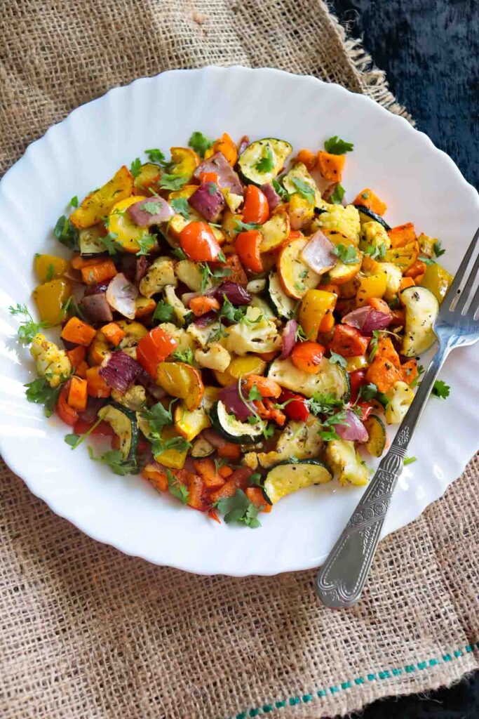 White plate with air fried vegetables garnished with fresh cilantro