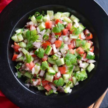 Kachumber served in a black bowl garnished with chili and coriander