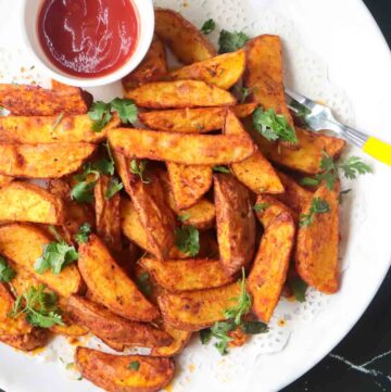 Air Fryer Potato Wedges served in a white plate with tomato ketchup