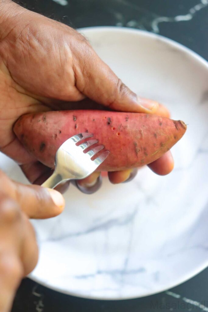 poking holes in sweet potato using a fork to prevent bursting while baking