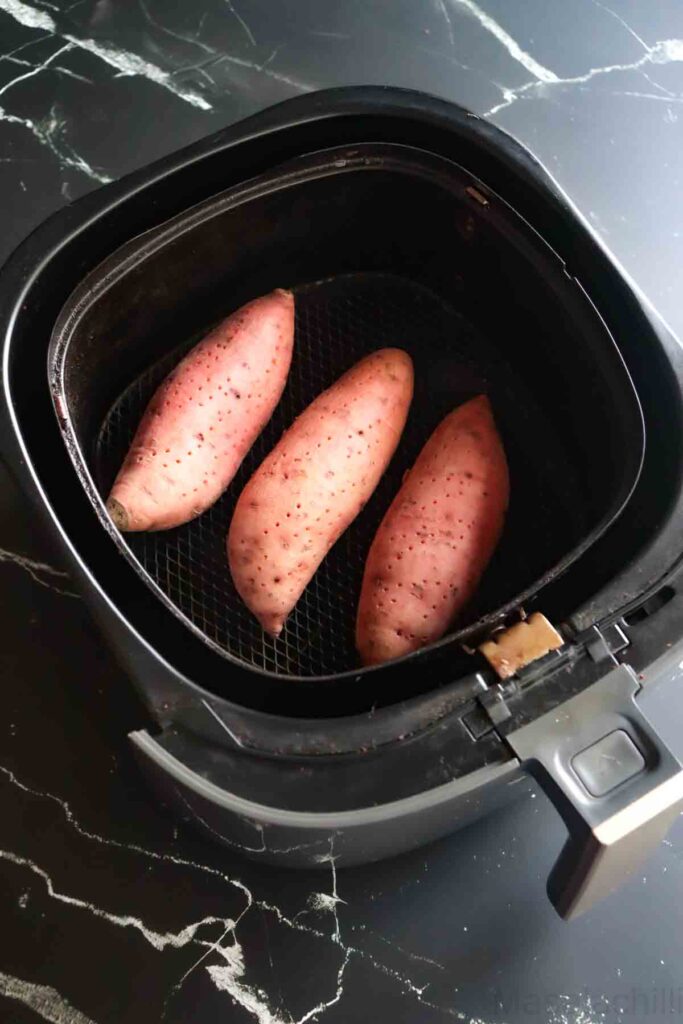 3 sweet potatoes placed in an air fryer basket for baking