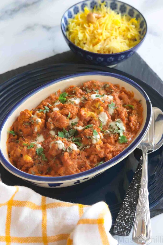 cauliflower tikka masala served in a blue bowl with saffron rice