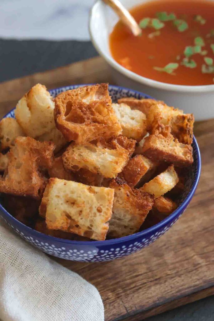 Bowl of homemade air fryer croutons served with tomato soup