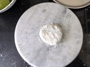 flatten the dough ball on the board for rolling